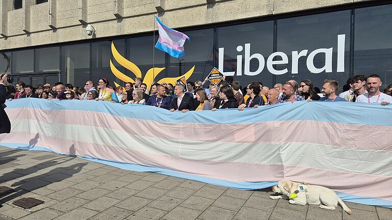 Lib Dem campaigners holding a large trans flag.